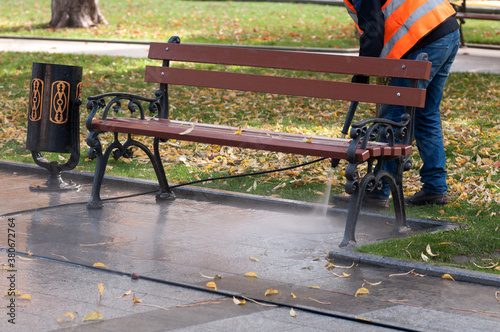 strong pressure of water wash the street, cleaning the park area in autumn