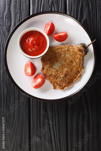 Tortang talong is a Filipino omelette made by pan frying grilled whole eggplants dipped in an egg mixture close-up in a plate on the table. Vertical top view from above photo