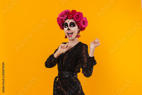 Photo of girl in halloween makeup and flower wreath dancing on camera