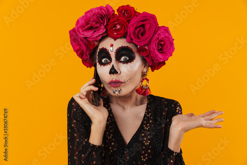 Photo of girl in halloween makeup and flower wreath talking on cellphone