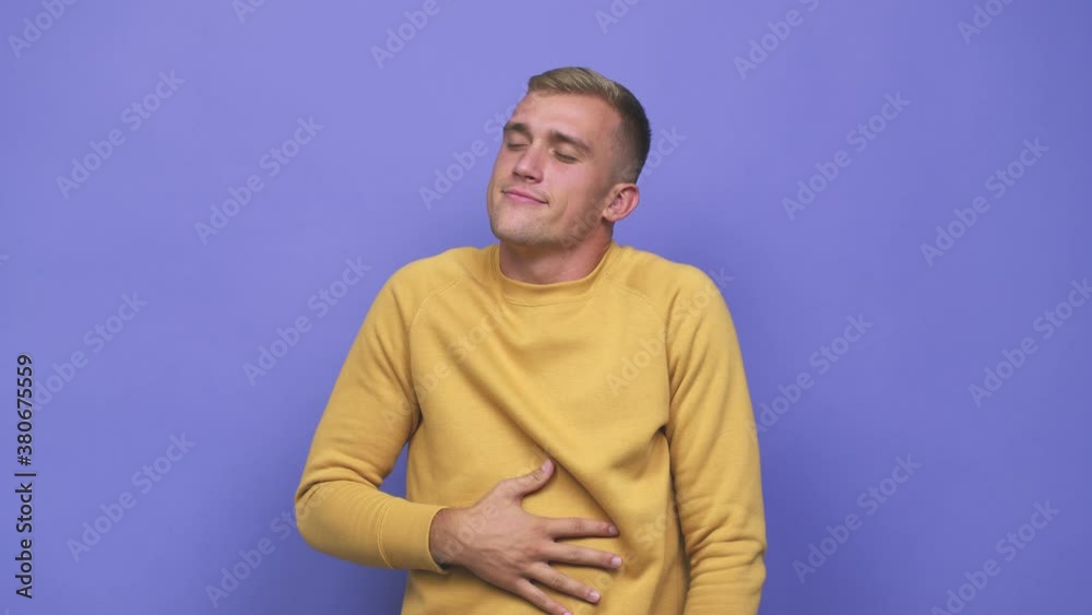 Young caucasian man touches tummy, smiles gently, eating and satisfaction concept Young caucasian man touches tummy, smiles gently, eating and satisfaction concept