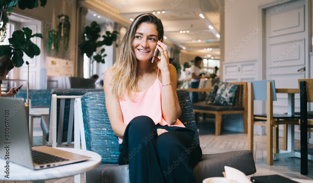 Smiling young woman having phone call in restaurant