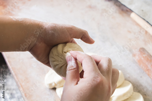 Image of making process of Chinese traditional food - baozi ( Chinese steamed buns ). Wrap the bun by folding the edge inwards.