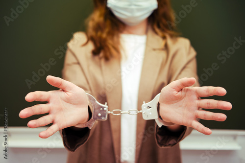 A school teacher in a medical mask with handcuffs, concept of captivity during the quarantine flu. Concept of problems at school during the coronavirus epidemic
