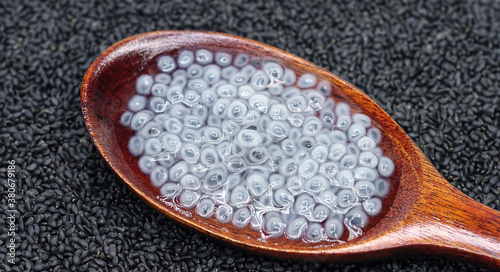 Basil seeds in wooden spoon on white background.