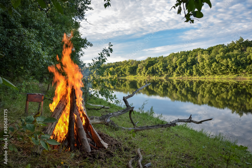 Naklejka premium bonfire on the background of the river and forest