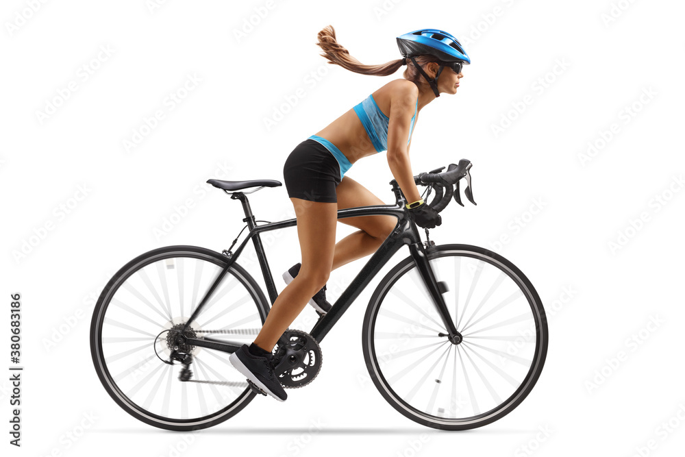Naklejka premium Full length profile shot of a woman in sportswear riding a bicycle with a helmet