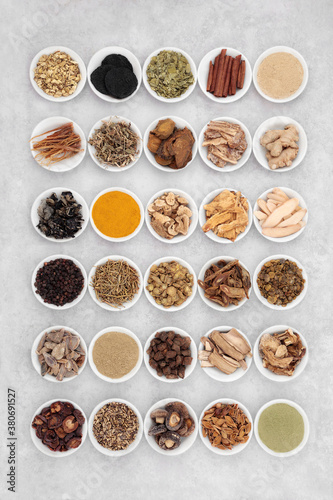 Large collection of Chinese fundamental herbs regularly used in herbal medicine, in porcelain bowls on grunge background. Flat lay.