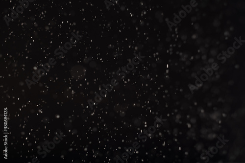 Snowfall background. Blur flying white flakes isolated on black. Winter night sky. Christmas blizzard. Defocused particles texture New Year decorative abstract wallpaper.