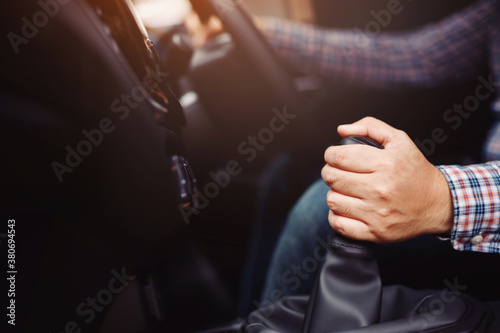 A man hand holding manual gearbox in car  he drives a new car at the showroom.