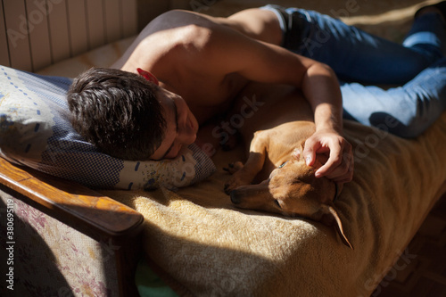 a guy ies on a bed with a dog photo