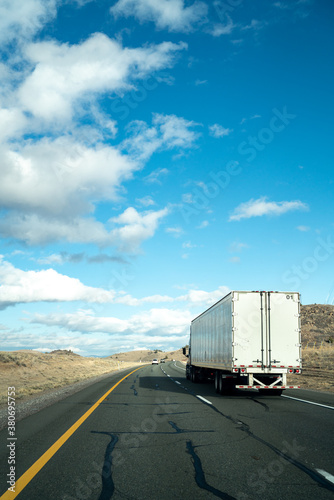 A semi truck driving down the freeway on a blue sky day photo