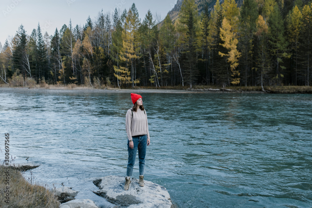 Young woman standing on a stone near the river Young woman standing on a stone near the river