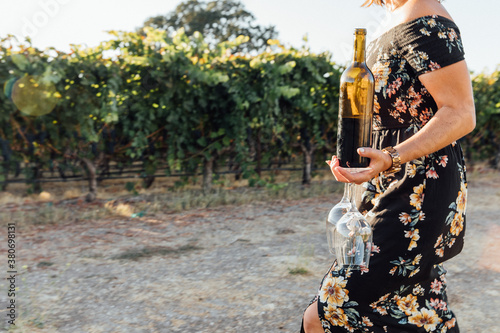 Woman Walks with a Wine Bottle in a Vineyard