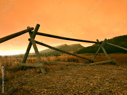 California, Oregon, Colorado wildfire orange smokey sky above rustic split log fence