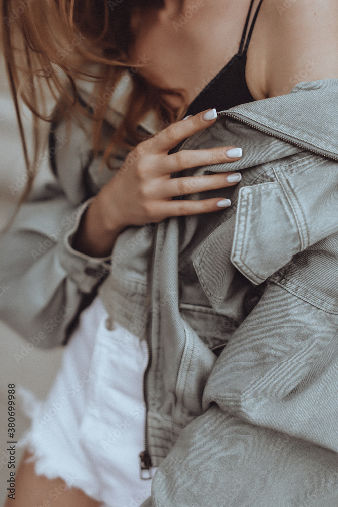 Close up of female hands with french manicure on a denim stylish jacket