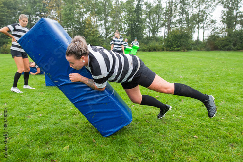 A female rugby player is tackling the tackle bag hard during pra
