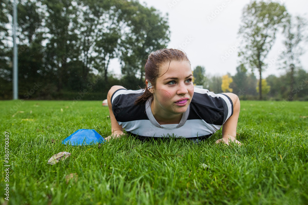 A female rugby player is lyiing on the grass during an exercise A female rugby player is lyiing on the grass during an exercise