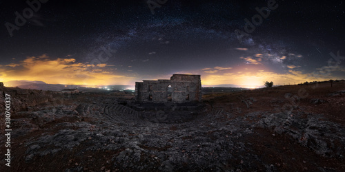 Wide angle ancient Roman theater of Acinipo city in remote landscape with colorful sunset sky on background photo