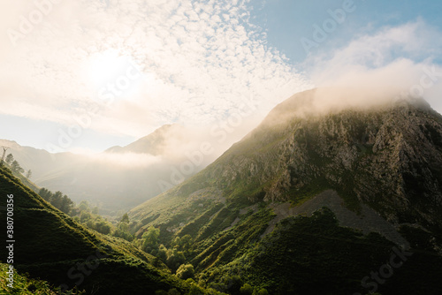Amazing landscape of highlands surrounded by fog in morning on background of blue cloudy sky