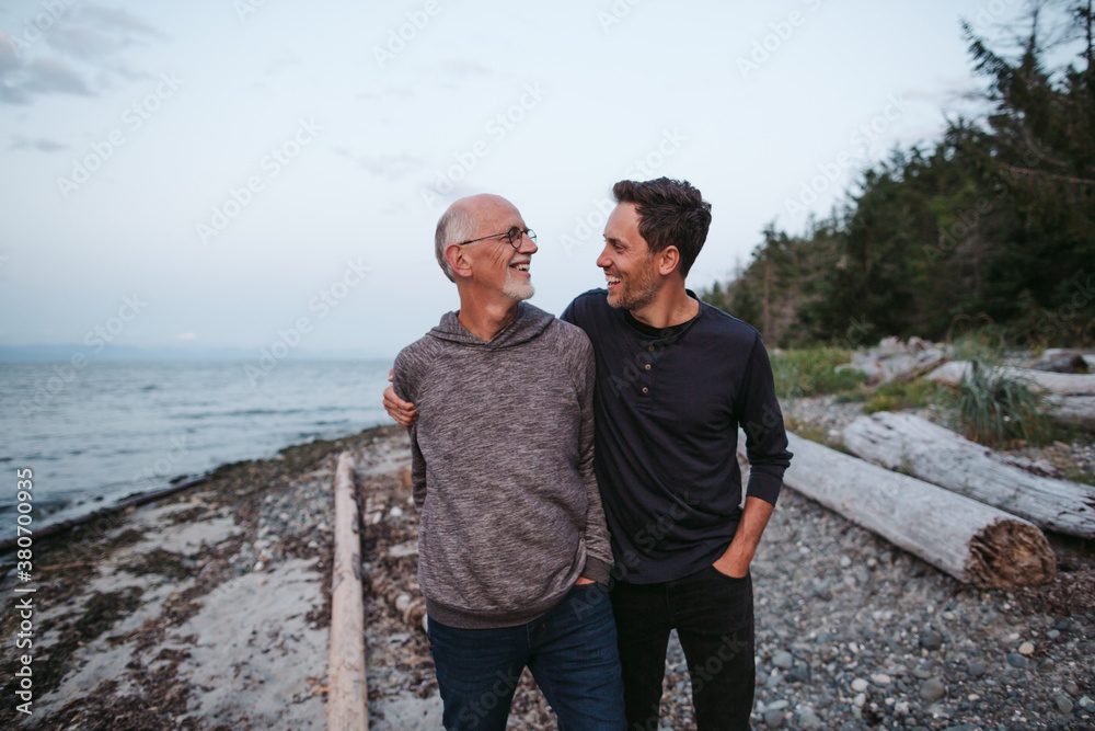 Father and mature son having fun together on the beach at sunset Father and mature son having fun together on the beach at sunset