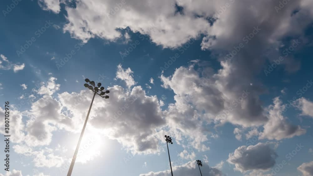 Timelapse with light towers of a football stadium against a sunset and summer clouds, cinematic fast and smooth movement of sky. Soccer stadium flashlights and evening time lapse. Timelapse with light towers of a football stadium against a sunset and summer clouds, cinematic fast and smooth movement of sky. Soccer stadium flashlights and evening time lapse.