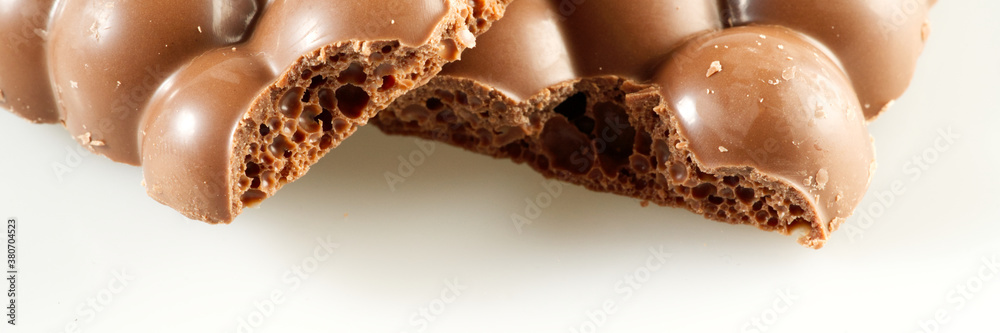 Tasty porous chocolate bar on white background. Sweet and tasty milk chocolate closeup, selective focus Tasty porous chocolate bar on white background. Sweet and tasty milk chocolate closeup, selective focus