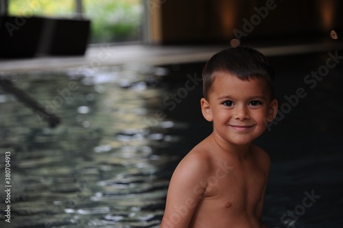Young boy sitting at the pool excited to go swimming