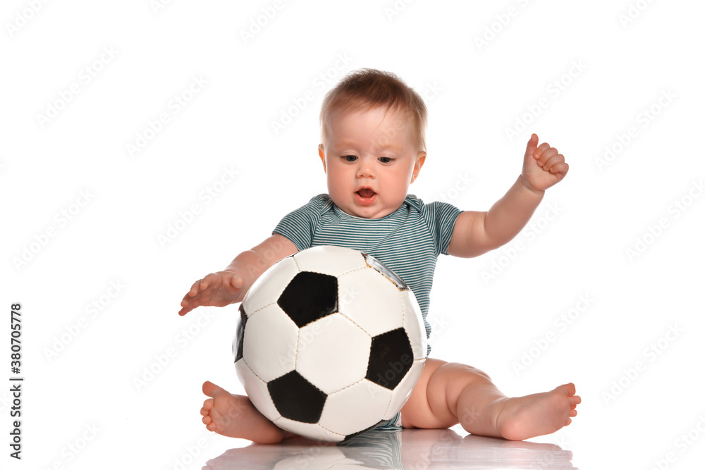 Baby boy sitting and playing a classic soccer ball on a white background.
