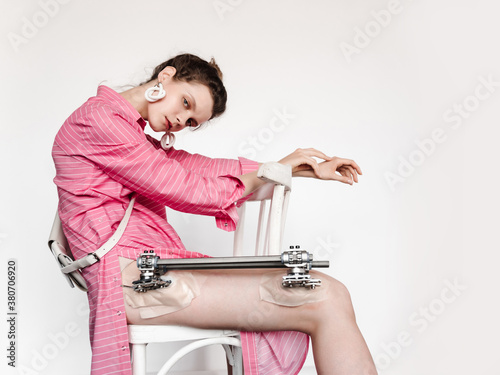 Young woman with external fixation sitting on chair
