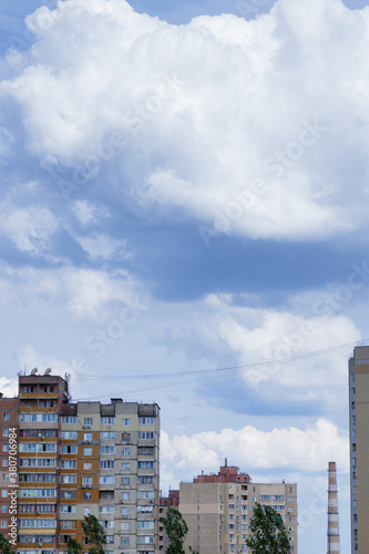 Cloudy blue sky and  huge cumulus clouds above the top of the buildings. © andriikomashko