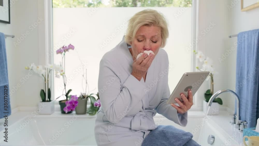 MS of a senior Caucasian woman sitting by bathtub feeling ill, using a tablet to call with a doctor. MS of a senior Caucasian woman sitting by bathtub feeling ill, using a tablet to call with a doctor.