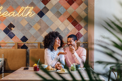 Cheerful black couple eating during date in restaurant photo