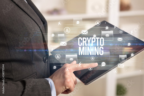 Close-up of a tablet searching CRYPTO MINING inscription, modern technology concept © ra2 studio