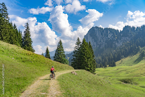 nice senior woman riding her electric mountain bike up to the Schreiber Sattel below Winterstaude summit in the Bregenzer Wald mountain range in Vorarlberg, Austria photo