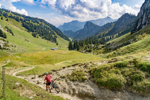 nice senior woman riding her electric mountain bike up to the Schreiber Sattel below Winterstaude summit in the Bregenzer Wald mountain range in Vorarlberg, Austria