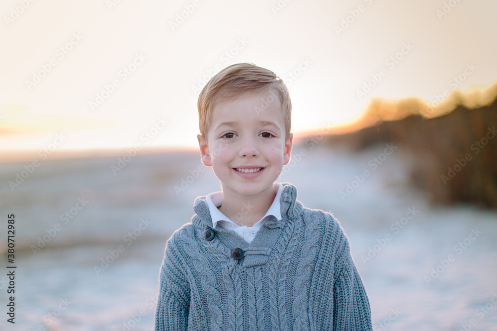 Close up portrait of a handsome young boy in a sweater standing on a beach Close up portrait of a handsome young boy in a sweater standing on a beach