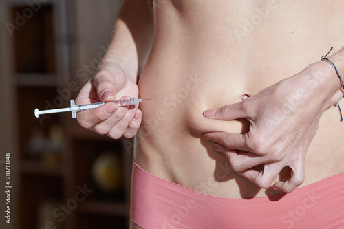 Girl making abdomen injection at home photo