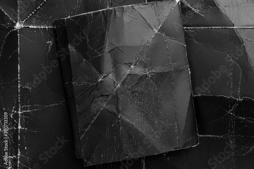 Black crumpled paper on a black shabby grunge background. Dark paper mock up for design