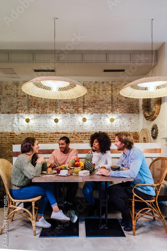 Multiethnic friends laughing at joke in cafe