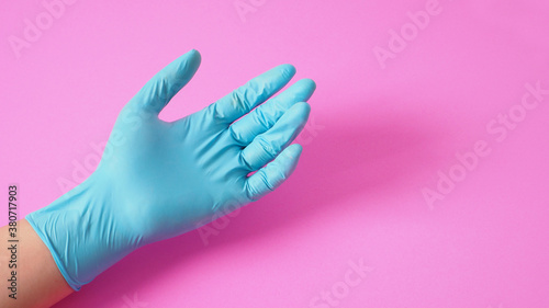 Hand is wear latex glove or doctor glove on pink background.