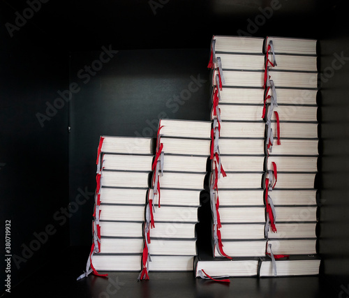 Gesangbücher liegen übereinander gestaptelt in einem schwarzen Bücherregal in einer katholischen Kirche