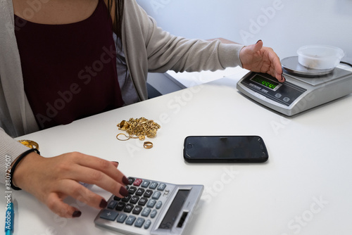 Gold dealer weighing and pricing value of gold jewellery photo