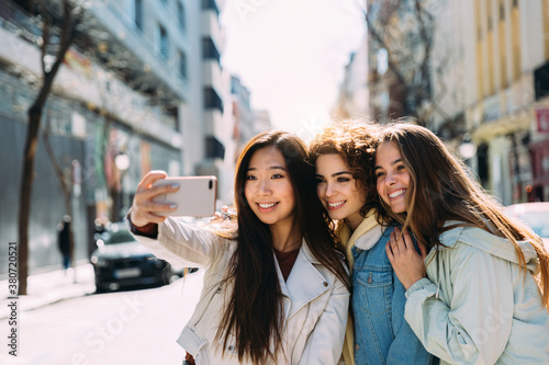 Multiracial female friends taking selfie in city