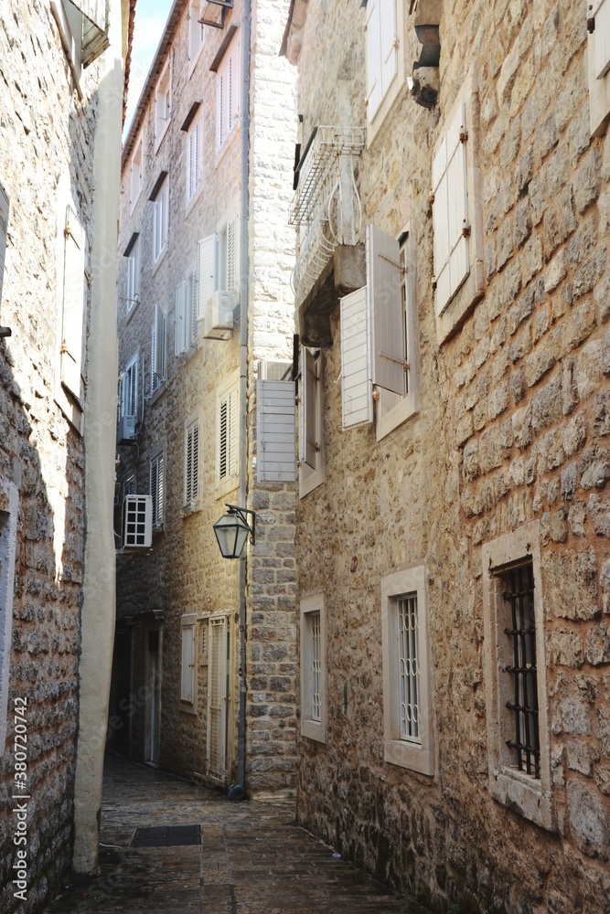 Narrow street and a brick wall buildings in old town od Budva, Montenegro