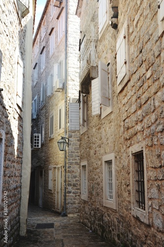 Narrow street and a brick wall buildings in old town od Budva, Montenegro © Marina