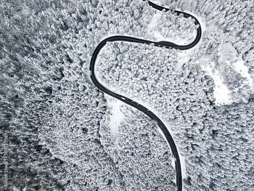 Beautiful aerial view of a curvy winding road with serpentine and white snow trees