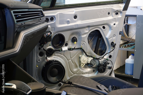 The inner lining has been removed from the door of a modern car. In the doorway you can see the wiring, the music speaker, the power window motor. Car service and electrodiagnostics Concept.