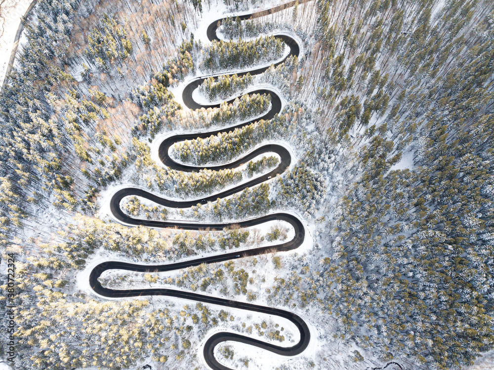 aerial view of a curvy winding road and white snow trees, winter.