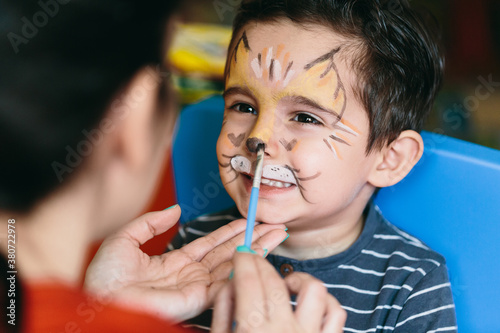 Happy mother putting makeup on her son. photo